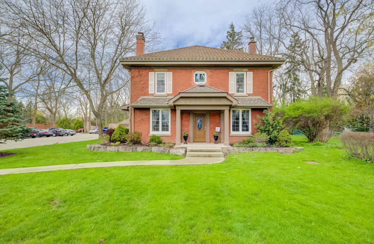 The Windmill House, a red-brick century home on a wide green lawn